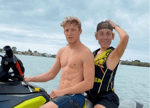 two young men are sitting on a jet ski in the water