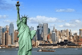 the statue of liberty is standing in front of a city skyline in new york city .