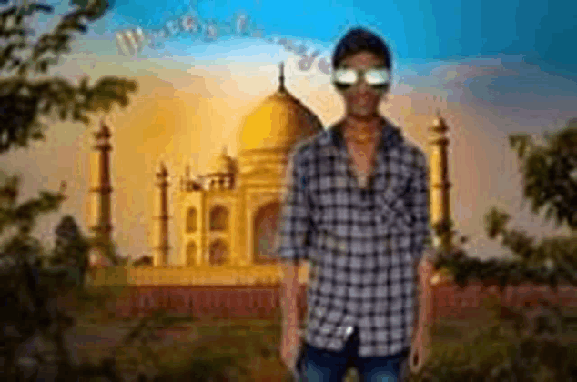 a young man wearing sunglasses is standing in front of a mosque .