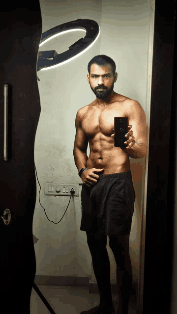 a shirtless man taking a picture of himself in a mirror