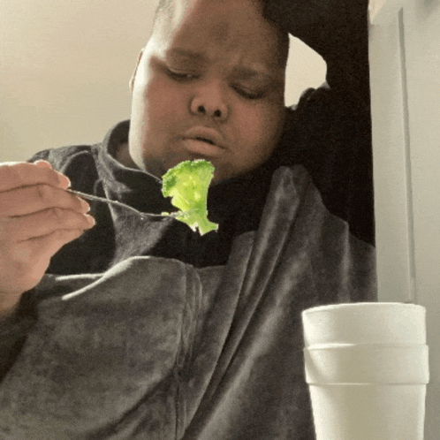 a man is eating a piece of lettuce with a spoon