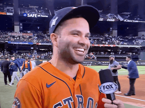 a man in an astros jersey is holding a microphone