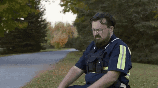 a man in a blue uniform with yellow stripes on the sleeves is sitting on the side of the road