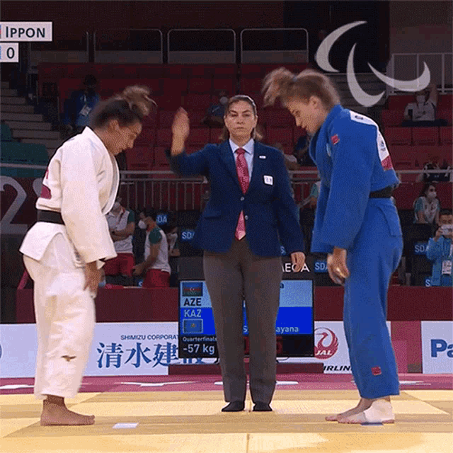 two female judo fighters are standing next to each other and one of them is wearing a blue uniform with aze on it