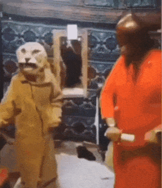 a man in a lion costume is standing next to another man in a red costume .