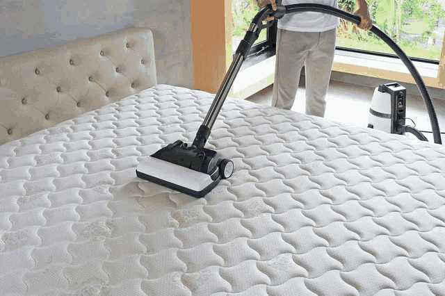 a person is using a vacuum cleaner on a mattress