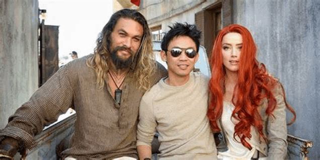 a man with a beard , a woman with red hair and a man with sunglasses are posing for a picture together .