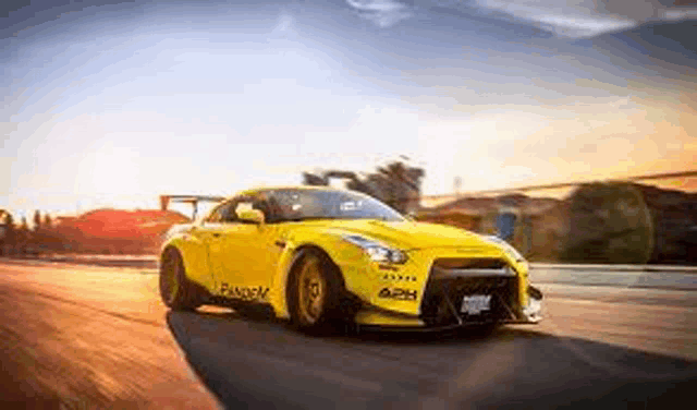 a yellow nissan gt r is driving down a road .