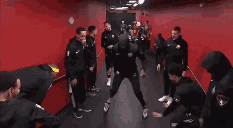 a man taking a picture of a group of basketball players in a locker room with the word finals on their sleeve