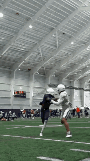 a football game is being played in an indoor stadium with a scoreboard showing a score of 29 to 0