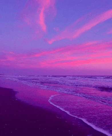 a purple sunset over a beach with waves crashing on the sand