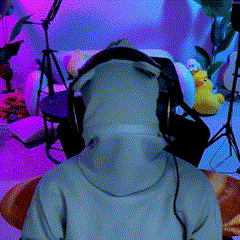 a person wearing headphones and a hoodie is sitting in a room