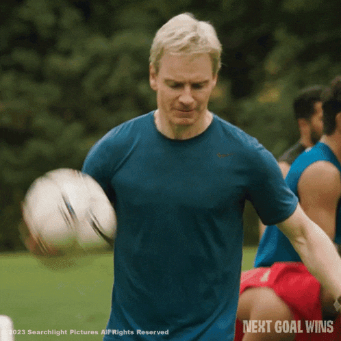 a man in a blue shirt is holding a soccer ball with the words next goal wins written below him