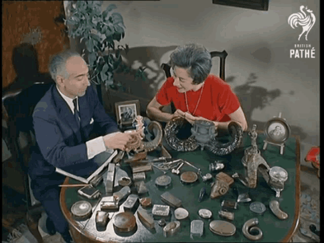 a man and a woman are sitting at a table with various items on it and the words pathe on the bottom right