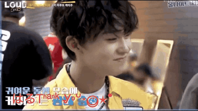 a young man wearing a yellow shirt is smiling and says thank you