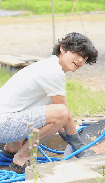 a young man is kneeling down next to a hose and smiling