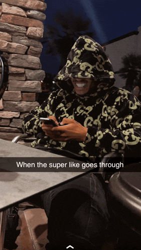 a man wearing a gucci hoodie sits at a table