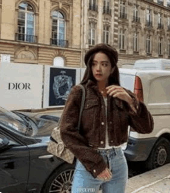 a woman wearing a brown jacket and a beret is standing in front of a dior store .