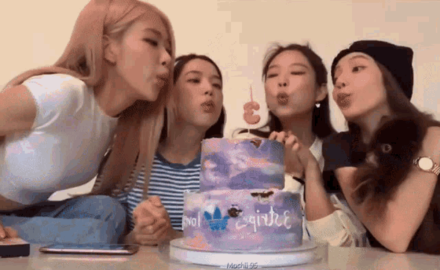 a group of girls are blowing out candles on a cake that says ' girlie ' on it