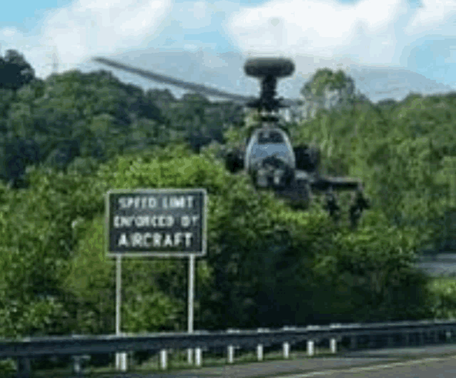 a helicopter is flying over a speed limit sign .