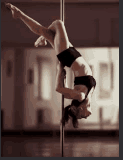 a pole dancer is doing a handstand on a pole