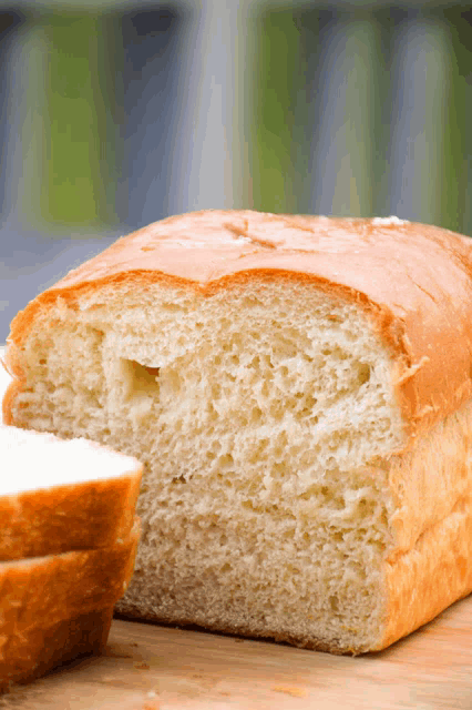 a loaf of bread with a slice taken out of it sits on a cutting board