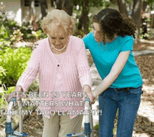 a woman helping an older woman walk with a walker