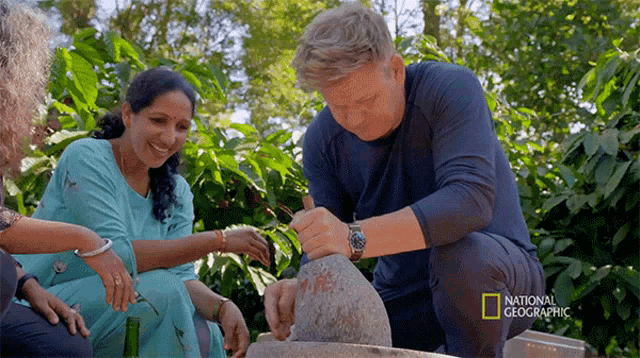 a man in a blue shirt is kneeling next to a woman in a blue dress and a national geographic logo