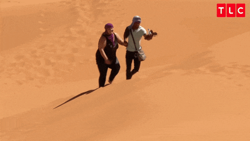 a man and a woman are walking down a sand dune with the words oh my god you 're lazy