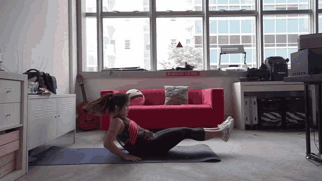 a woman is doing exercises on a yoga mat in front of a red couch with a sign that says " do not enter "