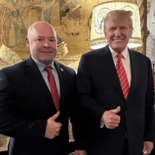 two men in suits and ties are giving each other thumbs up