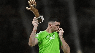 a soccer player in a green shirt is holding a trophy and a glove .