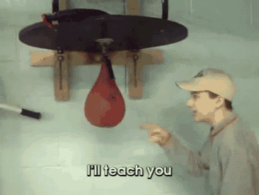 a man pointing at a punching bag that says i 'll teach you on it