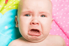 a baby is crying and making a funny face .