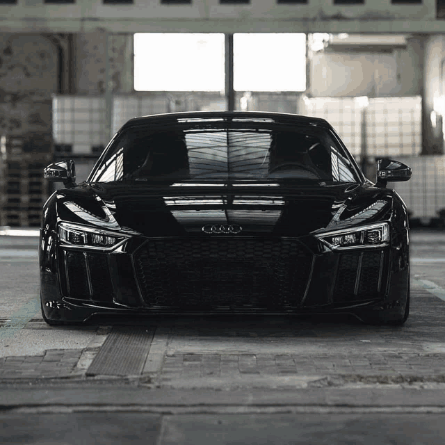 a black audi sports car is parked in a dark room