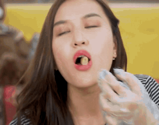 a woman wearing gloves is eating a piece of food with her mouth open