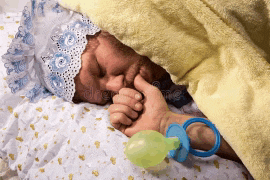 a baby is sleeping in a crib with a pacifier in its hand