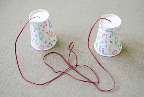 two paper cups with numbers on them are connected by red string