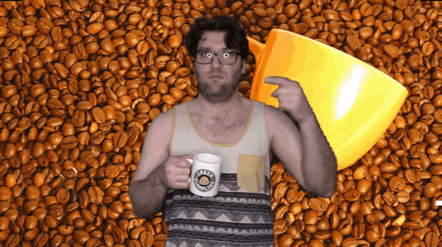 a man holding a mug that says ' caffeine ' on it in front of a pile of coffee beans