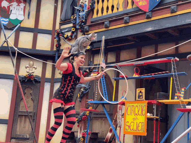 a woman performs a trick with a cat on her head in front of a sign that says circus seller