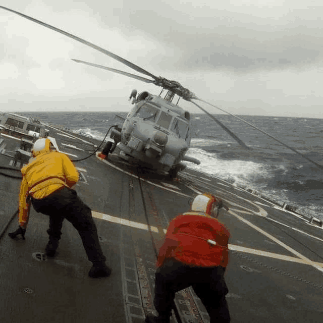 two men are pulling a helicopter from the water