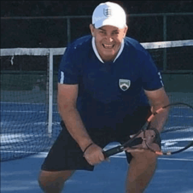 a man in a blue shirt is holding a tennis racquet on a tennis court .