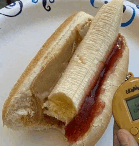 a paper plate with a hot dog with a banana and jam on it