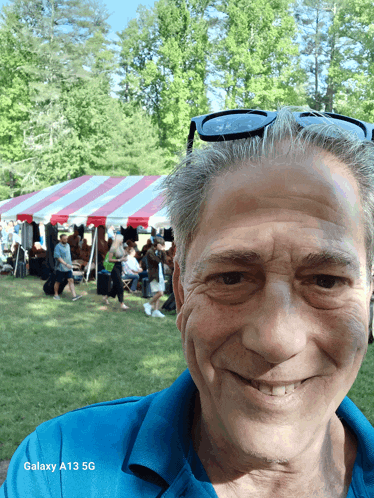 a man taking a selfie with a galaxy a13 5g behind him