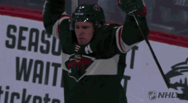 a hockey player with his arms in the air in front of a sign that says ' season wait '