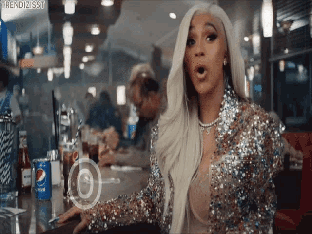 a woman in a sequined jacket is sitting at a diner table with a can of pepsi in front of her