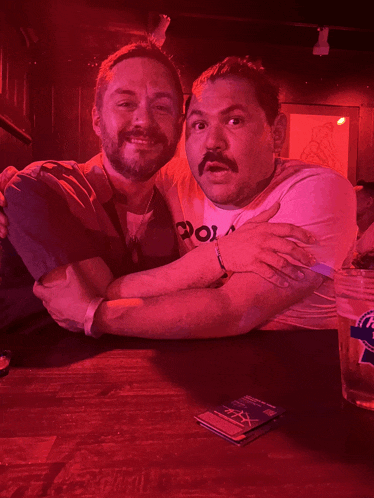 two men posing for a picture with one wearing a shirt that says " po "