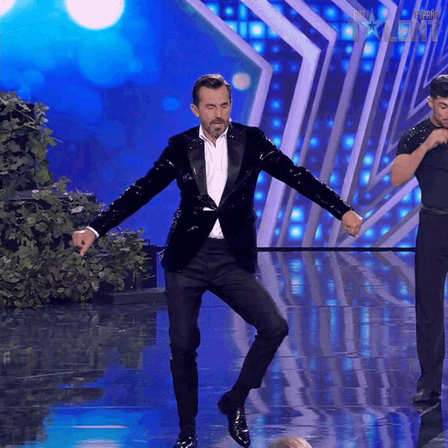 a man in a tuxedo is dancing on a stage in front of a sign that says ' talent ' on it