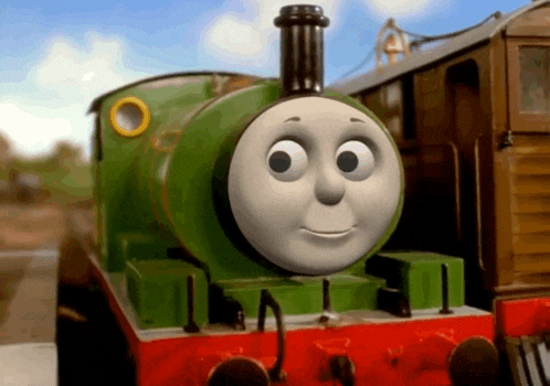 a green and red train with a cartoon face on it