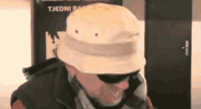 a man wearing a bucket hat and sunglasses is talking on a cell phone